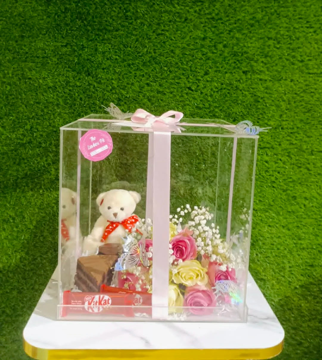 Acrylic gift box with mini teddy, brownies, cookies and flower bouquet for gifting.