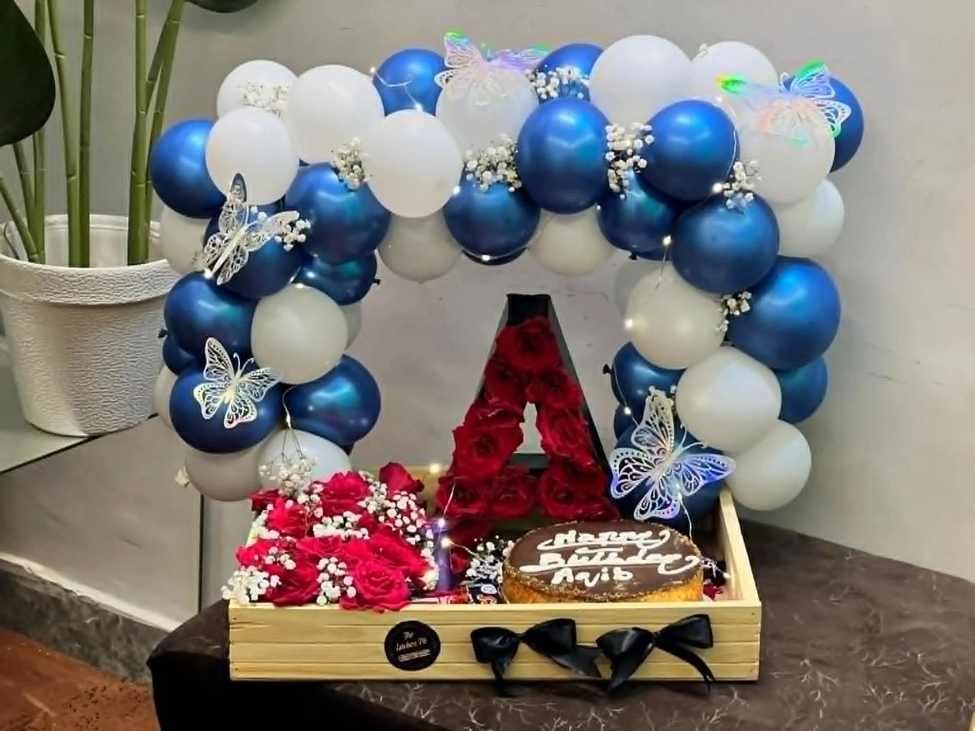Blue white balloon arch setup for him with 2.5 lbs cake red rose bouquet chocolates and LED letter Pakistan delivery