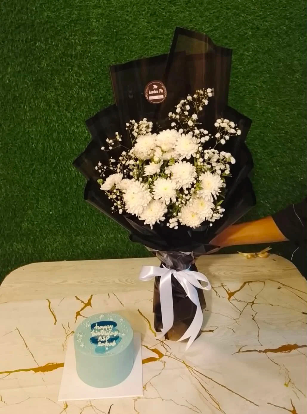 Cute birthday combo for him with a mini white chrysanthemum bouquet and blue-themed 2 lbs birthday cake, available for gift delivery in Islamabad.