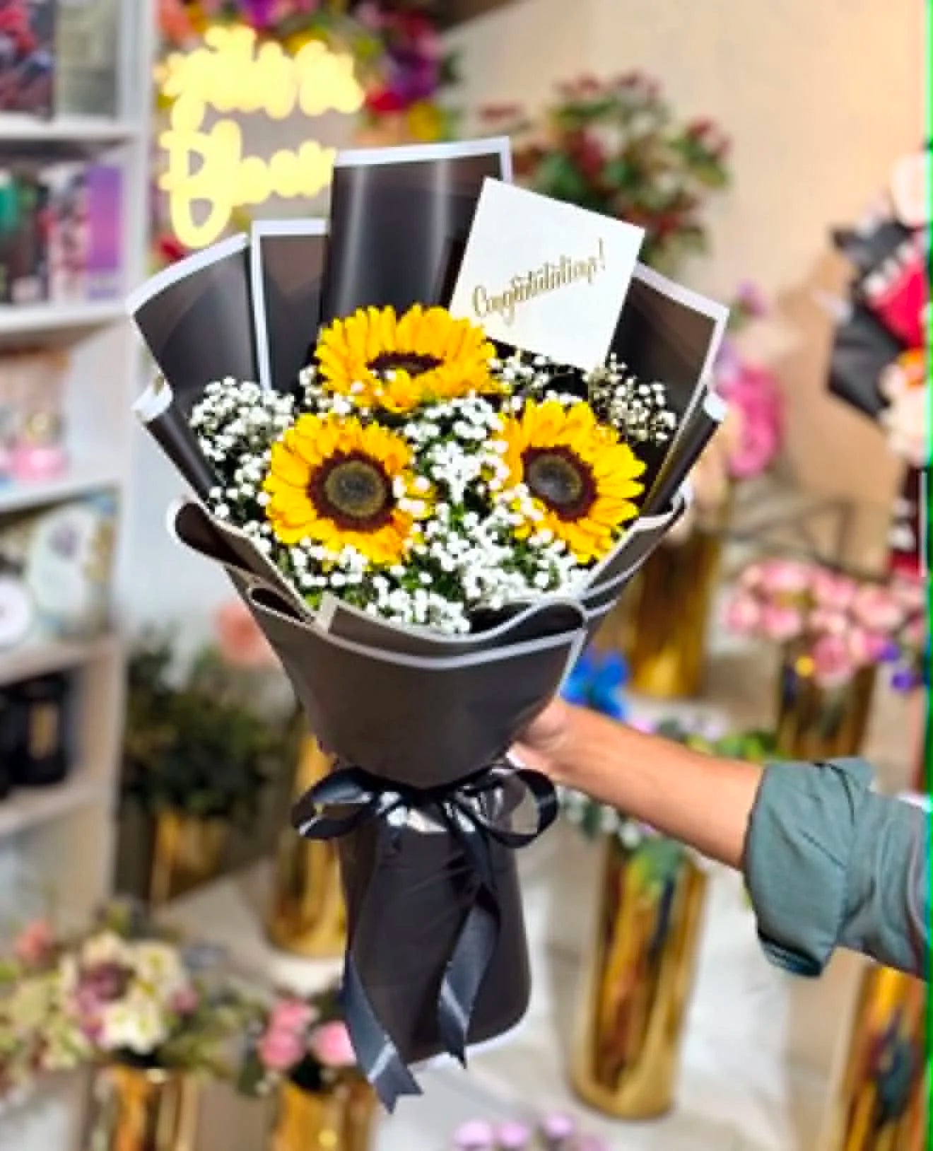 Mini sunflower graduation bouquet elegantly wrapped in black, perfect for congratulating graduates and celebrating academic achievements in Islamabad.