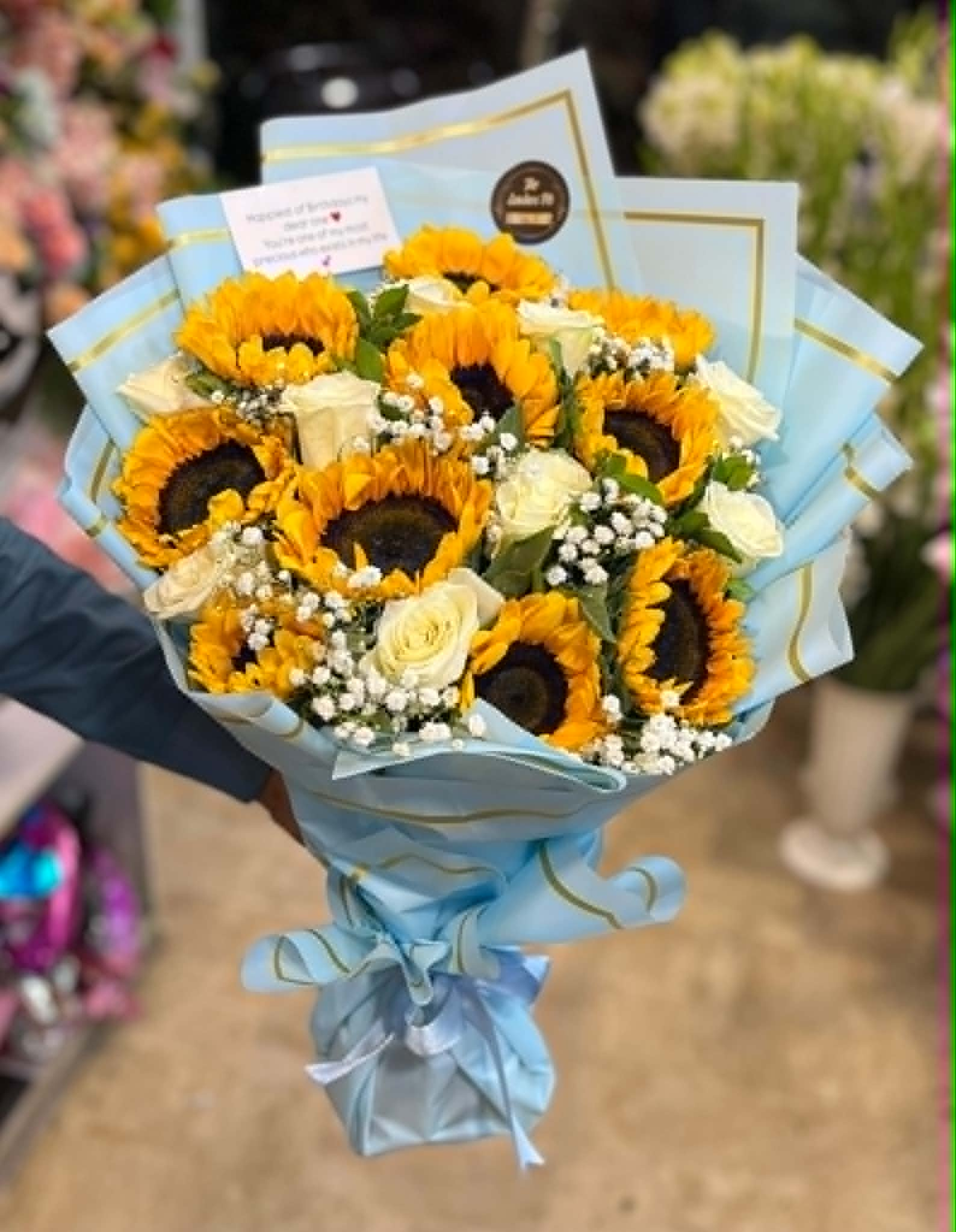 Luxury bouquet for him with imported white roses and fresh sunflowers, beautifully wrapped for birthdays, congratulations, and flower delivery in Pakistan.