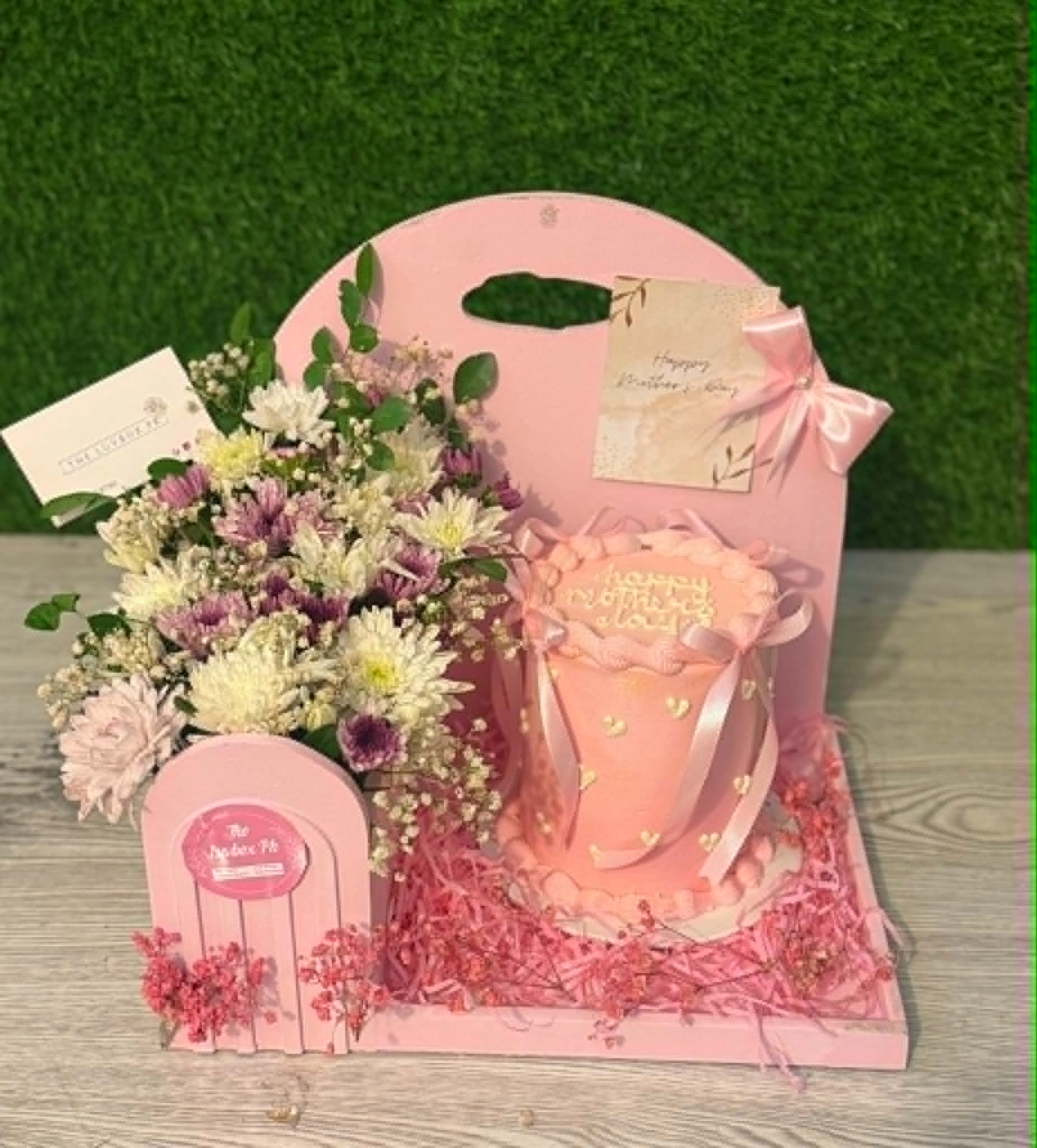 Luxury Mother’s Day gift box with 2 lbs cake and pink white floral arrangement, beautifully designed for Mother’s Day gifts delivery in Pakistan.