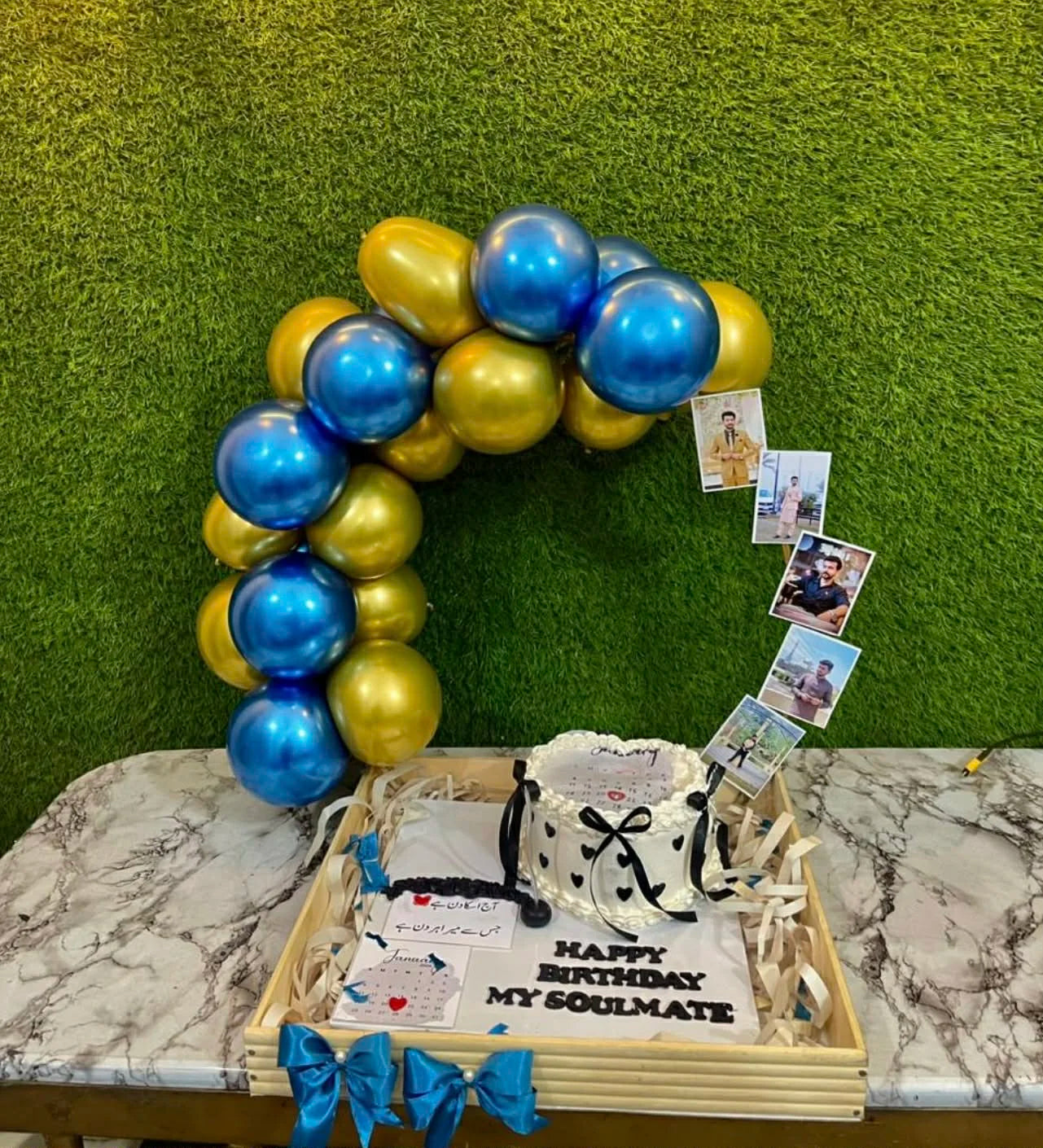Wooden tray gift basket with cake, balloon arch and personalized photos attached.
