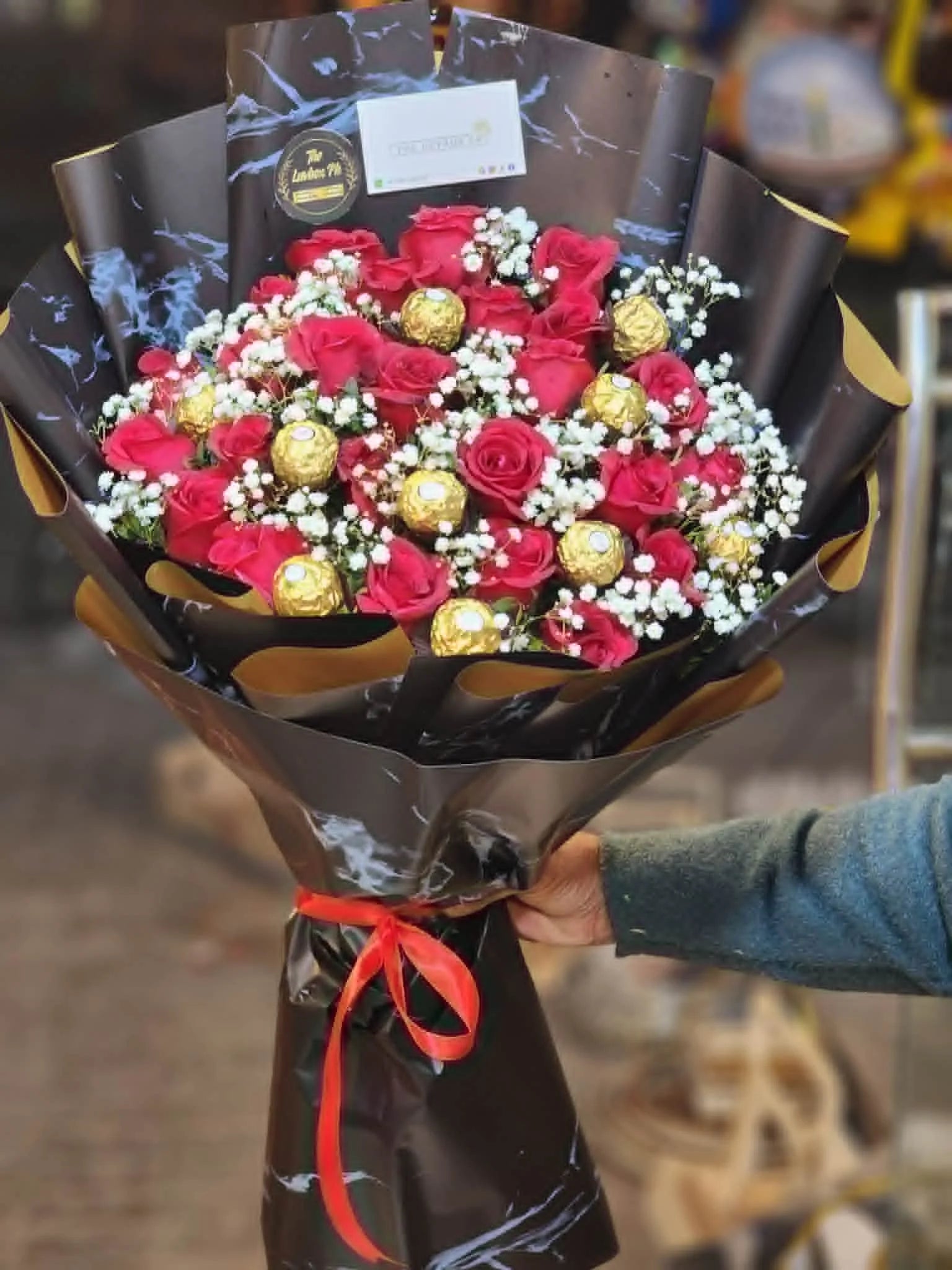 Red rose and Ferrero Rocher bouquet wrapped in black for romantic gifting.