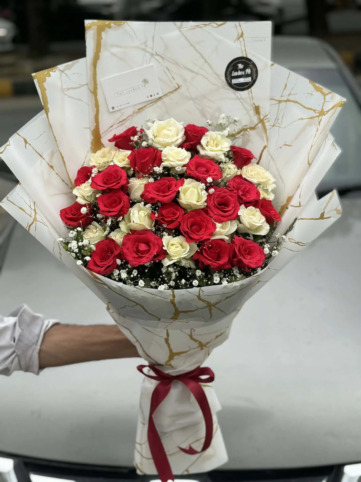 Affordable red and white local rose bouquet beautifully wrapped.
