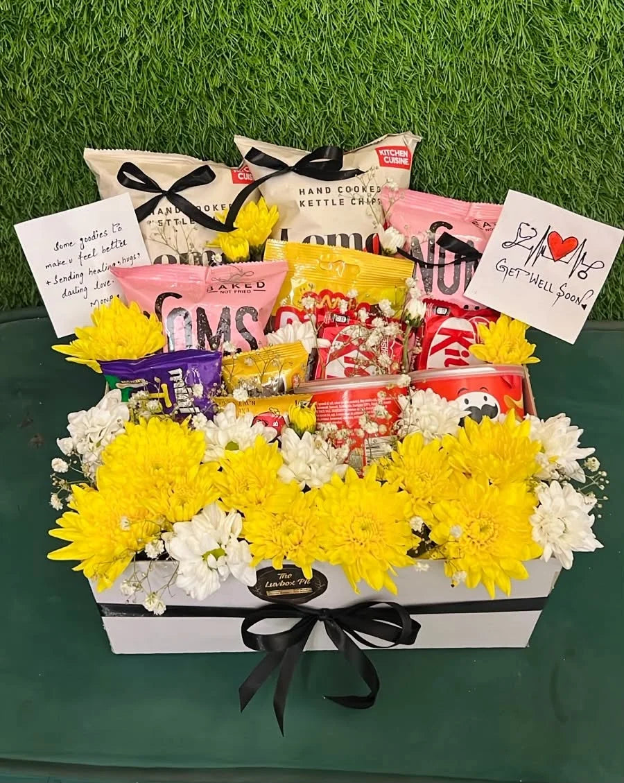 Premium Get Well Soon gift box with white and yellow flowers, assorted chocolates, Pringles and mixed snacks for delivery in Pakistan