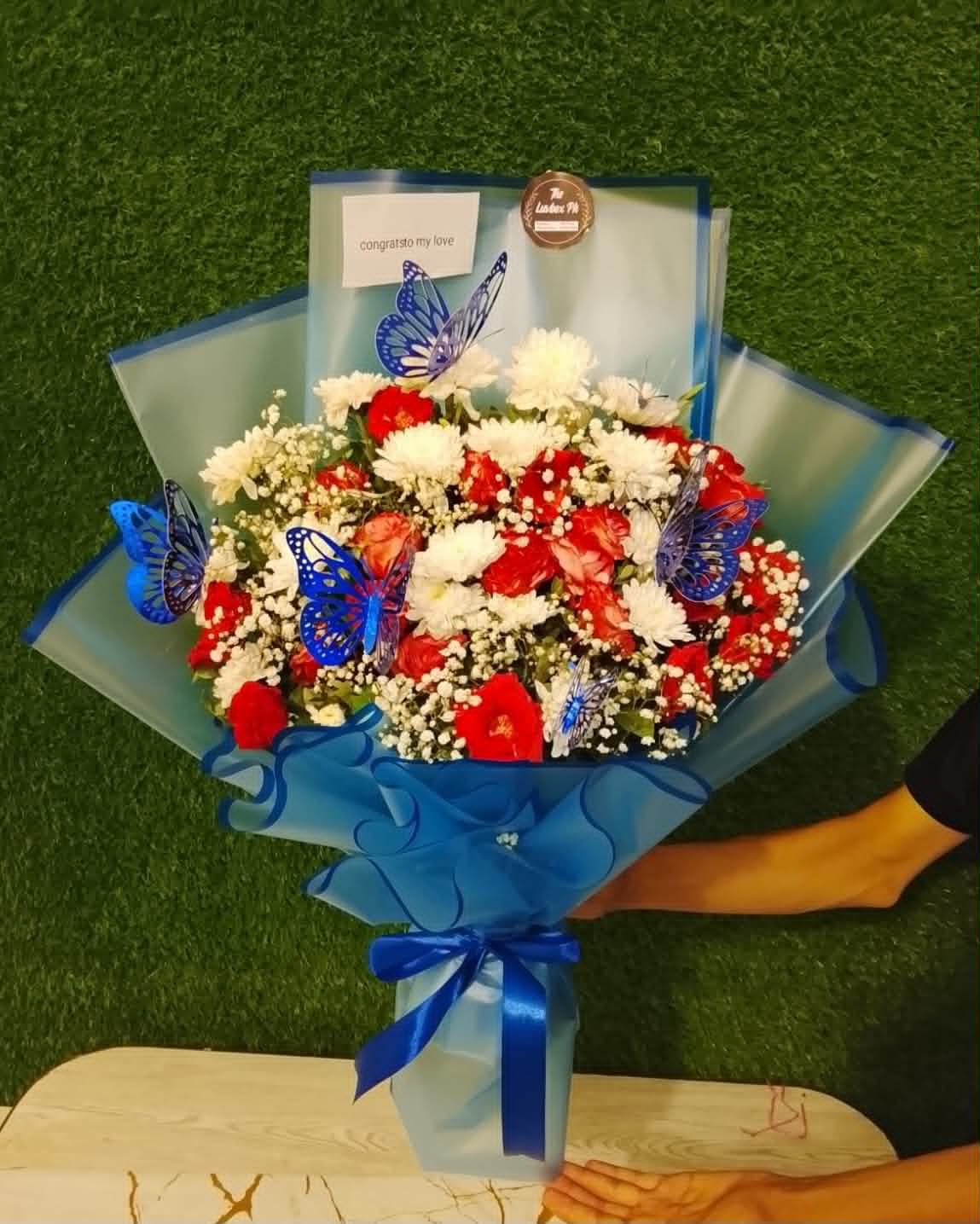 Luxury bouquet for him with white chrysanthemums, red roses, blue Baby's Breath, and elegant blue wrapping for birthdays and special occasions in Pakistan.