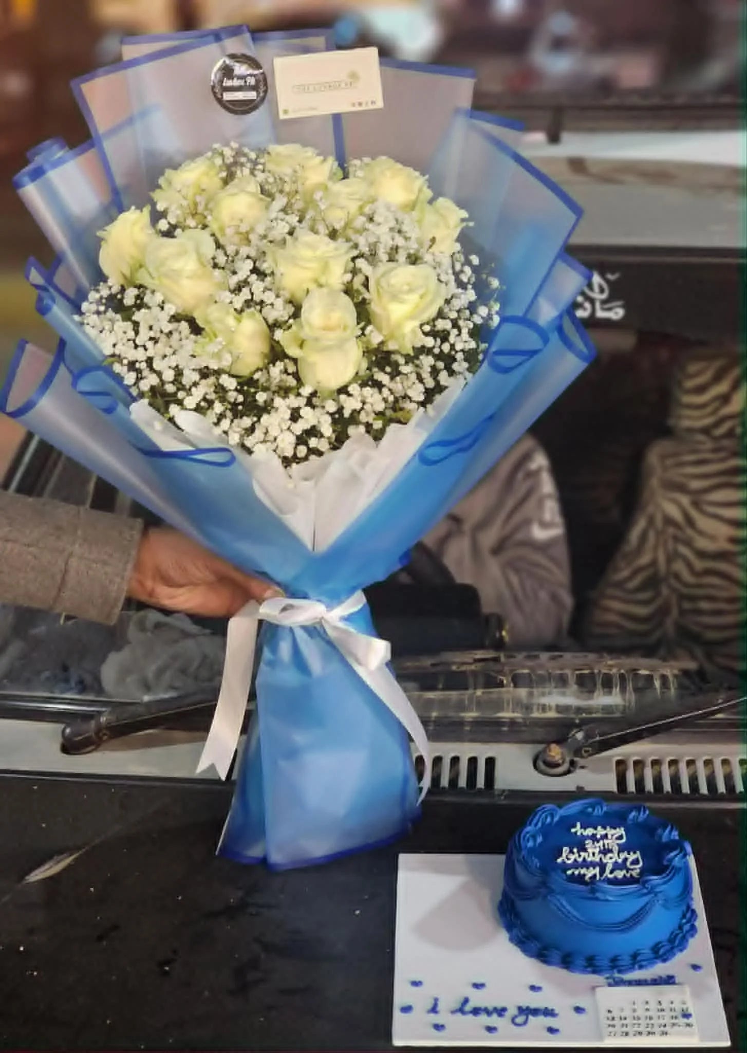 Oversized white rose bouquet with blue themed cake tray and calendar attachment for him.